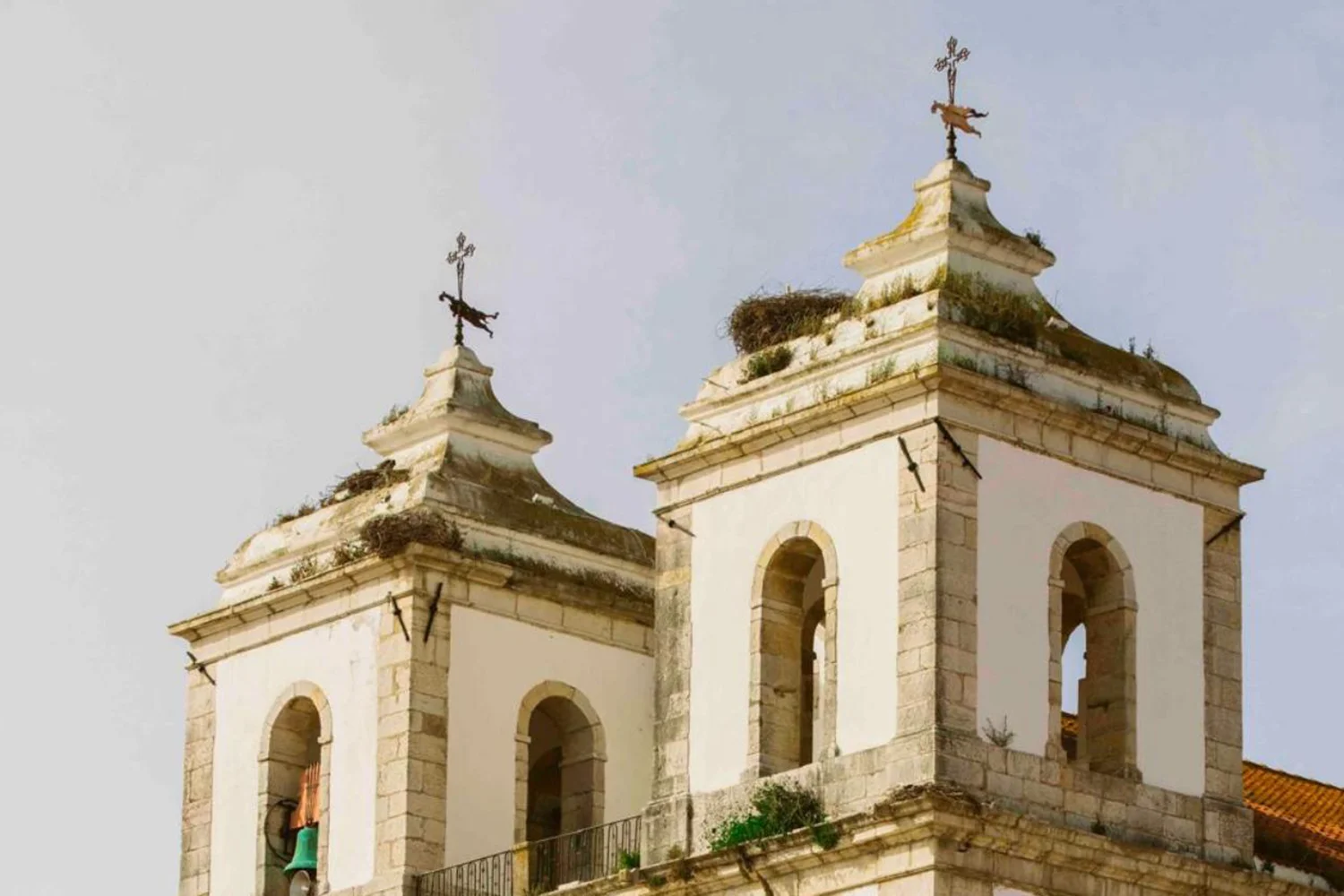 Twin whitewashed bell towers of a historic church in Alcácer do Sal, Alentejo, with stork nests on the rooftops